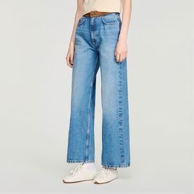 Model wearing Sandro clear wide-leg jeans with brown belt, styled with white trainers