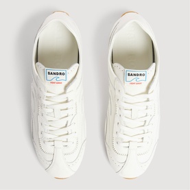 Sandro white leather trainers with lace-up front, branded tongue tab, and gum sole, top-down view