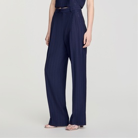 Model wearing navy wide-leg trousers with subtle texture, styled with a matching top, thin belt, and strappy flat sandals