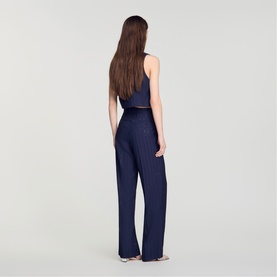 Model wearing navy blue pleated wide-leg trousers with matching sleeveless crop top, back view