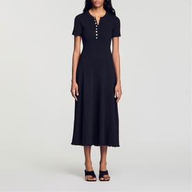 Model wearing Sandro Womens French Dress in black, midi length with short sleeves, V-neck button placket and flared skirt, styled with black heeled