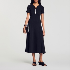 Model wearing Sandro Womens French Dress in black, midi length with short sleeves and button placket, styled with black mules and clutch bag.