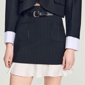 Model wearing Sandro black pinstripe mini skirt with white frill hem and patch pockets, styled with matching blazer and black belt