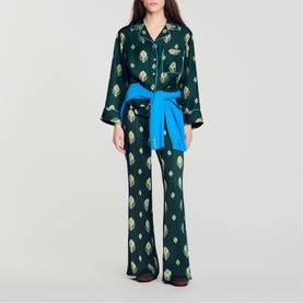 Model wearing Sandro green printed pyjama-style set with blue tie-waist belt and flared trousers