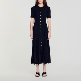 Model wearing Sandro Womens French Dress in black, ribbed knit midi length with button-through front and short sleeves, styled with black heeled mules