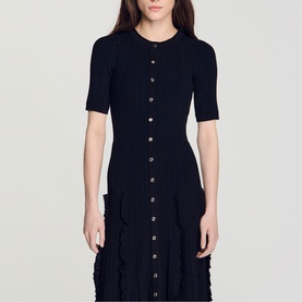 Model wearing Sandro Womens French Dress in black, short-sleeve knit midi with button-front placket and textured ruffle hem detail.