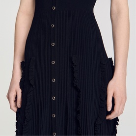 Model wearing Sandro Womens French Dress in black, featuring ribbed knit fabric, gold-tone buttons and fringed pocket detail.
