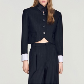 Model wearing Sandro black cropped blazer with contrast white cuffs and button front, styled with wide-leg tailored trousers