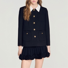 Model wearing Sandro black jacket with gold buttons, four patch pockets, and white collar, styled with a black ruffle mini skirt.