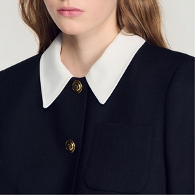 Model wearing Sandro Womens French Dress in black, featuring white Peter Pan collar and gold-tone buttons, close-up detail shot.