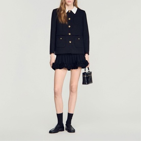 Model wearing Sandro Womens French Dress in black with ruffled hem and contrast white collar, styled with black mini bag and loafers