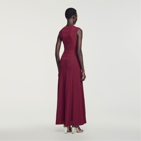 Model wearing Sandro Womens French Dress in red, sleeveless maxi with fitted bodice and flared skirt, back view, styled with silver heels