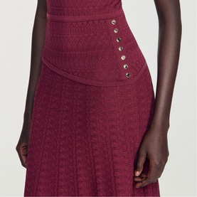 Model wearing Sandro Womens French Dress in red knit fabric, featuring high waist panel with silver stud detail and flared skirt.