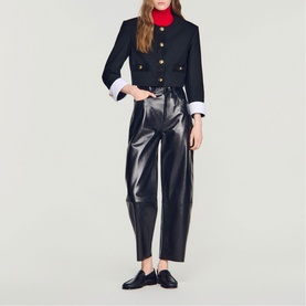 Model wearing Sandro black cropped military jacket with gold buttons, styled with red roll neck, black faux leather trousers and loafers