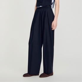 Model wearing Sandro wide-leg navy blue tailored trousers with pleated front, styled with brown loafers