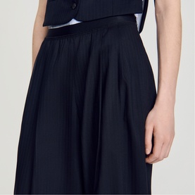 Model wearing Sandro Womens French Dress in navy blue, full pleated midi skirt, styled with a navy waistcoat
