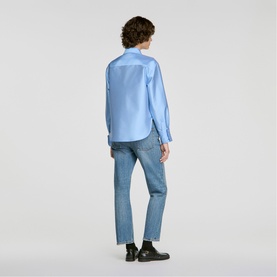 Model wearing Sandro sky blue long-sleeve shirt, styled with blue denim jeans and black shoes, back view.