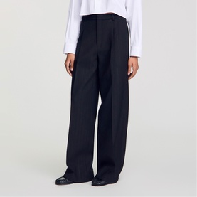 Model wearing Sandro Pinstripe High-Rise Wide Leg Trousers in black, with wide-leg silhouette and pleat details, styled with a white shirt.