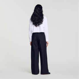 Model wearing Sandro Pinstripe High-Rise Wide Leg Trousers in black, rear view, styled with a white long-sleeve top.