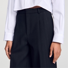 Model wearing Sandro Pinstripe High-Rise Wide Leg Trousers in black, featuring wide-leg silhouette, vertical stripes and pleat details, styled with a