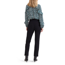Model wearing Phase Eight black slim-leg trousers, styled with a teal and white spot print ruffle blouse, shot from behind.