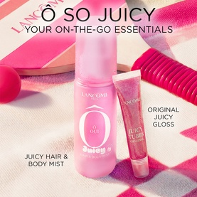 Lanc&ocirc;me &Ocirc; So Juicy hair and body mist with Juicy Tubes lip gloss in pink packaging, styled with pink accessories on a striped surface.