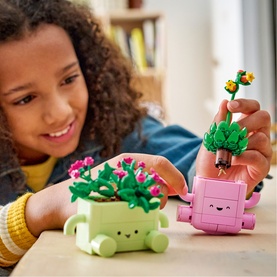 Child playing with Lego Botanical set featuring green and pink character plant pots with pink floral and green leafy builds
