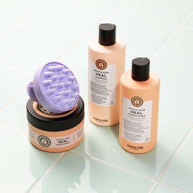 Maria Nila Head & Hair Heal conditioner, shampoo, hair mask and purple scalp massager brush set on tiled surface