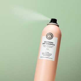 Maria Nila Soothing Dry Shampoo aerosol can in nude pink, shown spraying, on sage green background