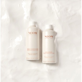 Neom Organics Body Lotion in Natural, two bottles shown side by side on a wet marble-effect surface.