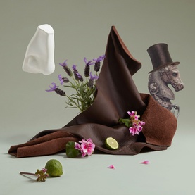Penhaligon EDP fragrance styled with chocolate brown fabric, florals, lime, and illustrated bear figurine on sage green background