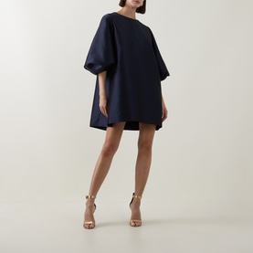 Model wearing Roisin Linnane Olivia Mini Dress in navy, oversized silhouette with voluminous puff sleeves, styled with nude strappy heels.