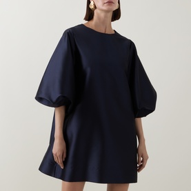 Model wearing Roisin Linnane Olivia Mini Dress in navy, featuring voluminous puff sleeves and A-line silhouette.