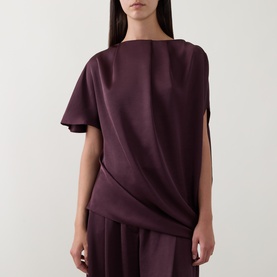 Model wearing Roisin Linnane Wine Top with draped front detail and short sleeves, styled with matching wide-leg trousers.