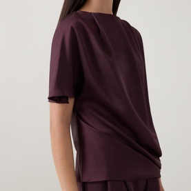 Model wearing Roisin Linnane wine top, short sleeves, relaxed fit with back detail, styled with matching wide-leg trousers