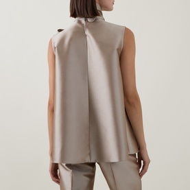 Model wearing Roisin Linnane Mya Bow-Detail Top in gold, sleeveless with back bow detail, styled with matching taupe trousers.