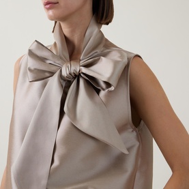 Model wearing Roisin Linnane Mya Bow-Detail Top in gold, sleeveless with oversized bow neckline detail