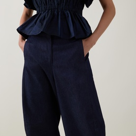 Model wearing Roisin Linnane navy cotton wide-leg trousers with front pockets, styled with matching navy ruffle top.