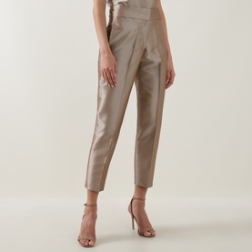 Model wearing Roisin Linnane Twig Cropped Slim-Leg Trousers in gold satin finish, tapered leg, mid-rise, styled with strappy heeled sandals.