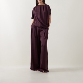Model wearing Roisin Linnane wine wide-leg trousers with matching draped top and open-toe heeled mules.