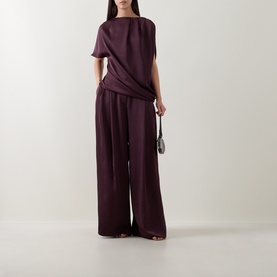 Model wearing Roisin Linnane Wine Trousers with matching wine short-sleeve top, styled with a small dark handbag.