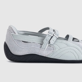 Puma white croc Mary Jane flat shoes with double buckle straps, cutout detailing, and black rubber sole.