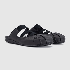 Puma black flat shoes with elasticated cross straps, split-toe detail, and smooth leather upper on a light sole.