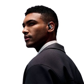 Model with black wireless in-ear earbuds, styled with a dark blazer, side profile view