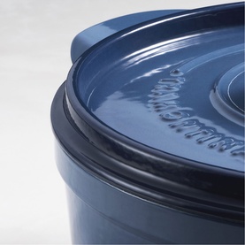 Tramontina blue cast iron casserole dish with fitted lid, close-up showing embossed logo and glossy enamel finish