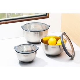 Tramontina stainless steel mixing bowls set of three with clear grey-rimmed lids, shown with lemons inside largest bowl on white surface