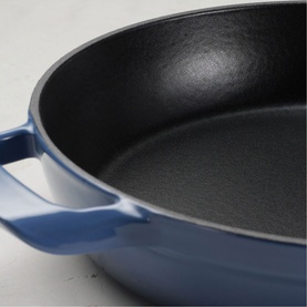 Tramontina blue cast iron pan with black non-stick interior, dual handles, angled close-up view