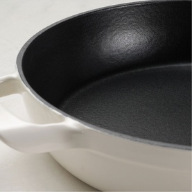 Tramontina latte skillet with black non-stick interior and twin handles, shown from above on marble surface