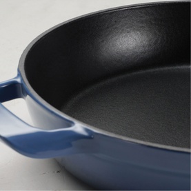 Tramontina blue cast iron skillet with black non-stick interior and dual handles, close-up detail view