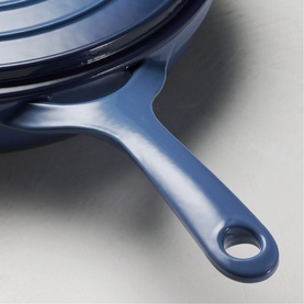 Tramontina blue cast iron saute pan handle detail with lid visible, smooth enamel finish and hanging hole